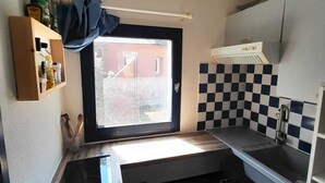 A compact kitchen with a window, a sink, a stove, and a checkered backsplash. - Fisherman's farmhouse between the swimming pool, the Etang de Salses-Leucate and the Mediterranean (Le Barcarès)