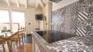 A modern kitchen with a glass-top island, wooden chairs, and patterned tiles. - Penthouse Bay View (Sestri Levante)