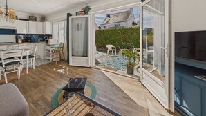 A spacious living area with a kitchen, dining table, and a large sliding glass door leading to a garden.