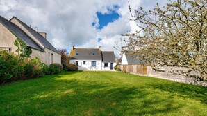 Une maison traditionnelle avec un toit en pente, une pelouse bien entretenue et un mur en pierre.