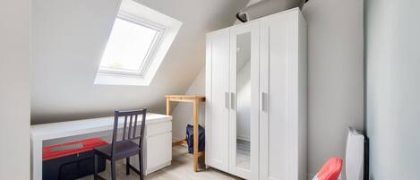 Une pièce comprenant un bureau, une chaise, une armoire et une fenêtre.