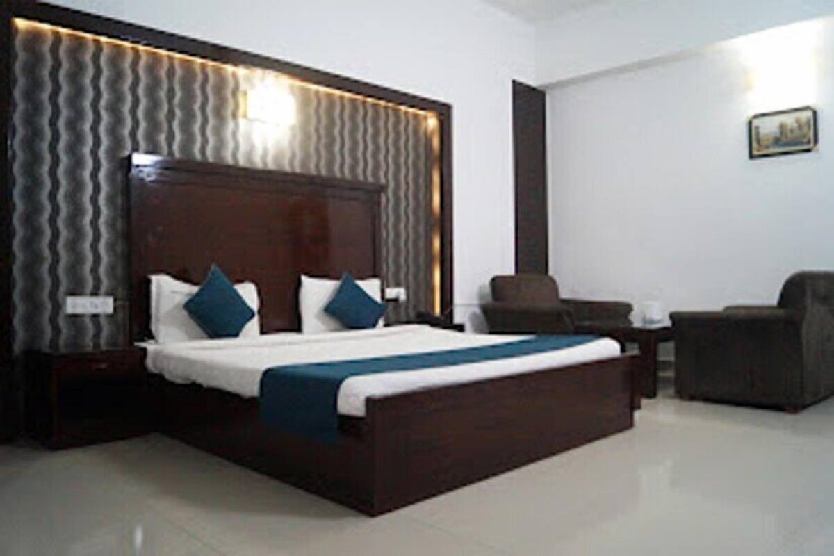 A modern hotel room with a large bed, a nightstand, a chair, and a small table.