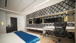 A modern hotel room with a large bed, a desk, and a chair. - BNGV Grandeur Hotel & Banquets (Bengaluru)
