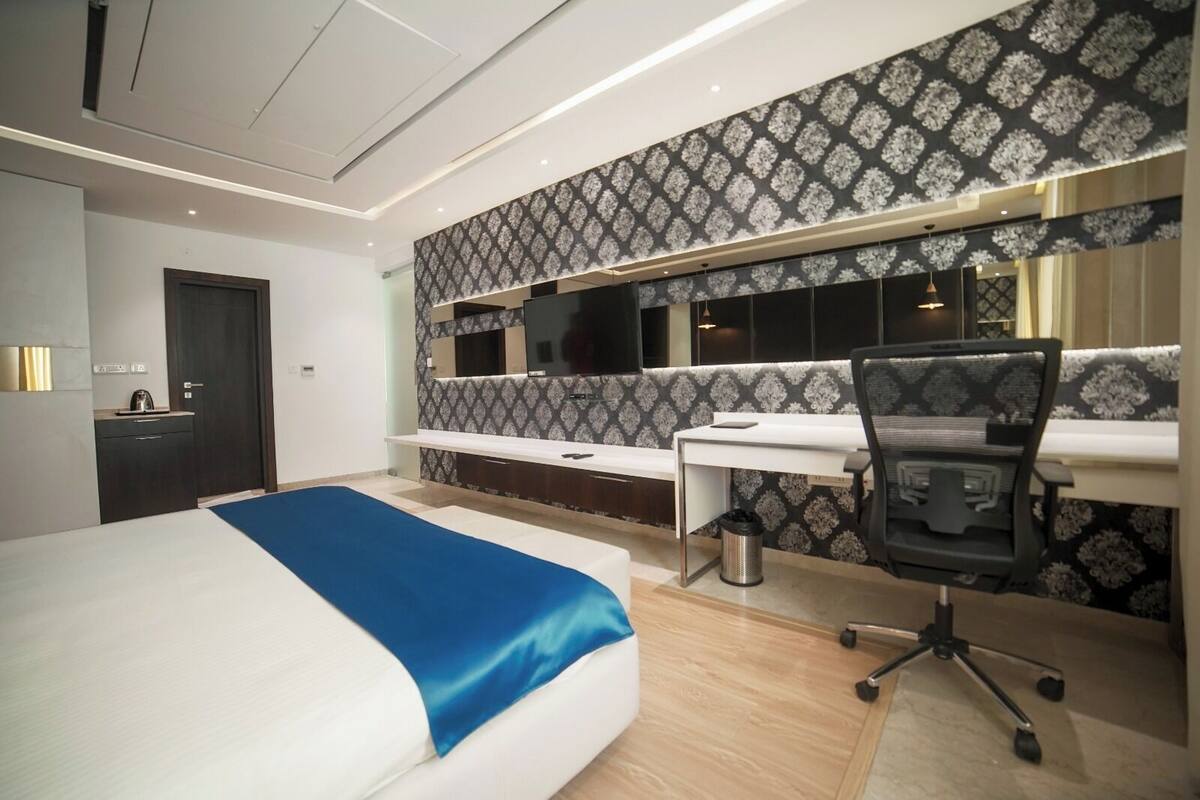 A modern hotel room with a large bed, a desk, and a chair.