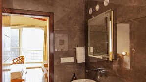 Een moderne badkamer met een grote spiegel, een houten wastafelmeubel en uitzicht op een balkon.