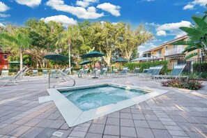 A pool area with lounge chairs and umbrellas, surrounded by trees and buildings. - Spacious 3BR retreat w/ pool access & park views (Kissimmee)