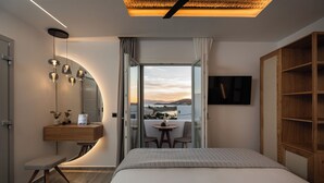 Una habitación de hotel moderna con una cama, un escritorio con una silla, una pequeña mesa con dos sillas, un televisor y vistas a la ciudad.