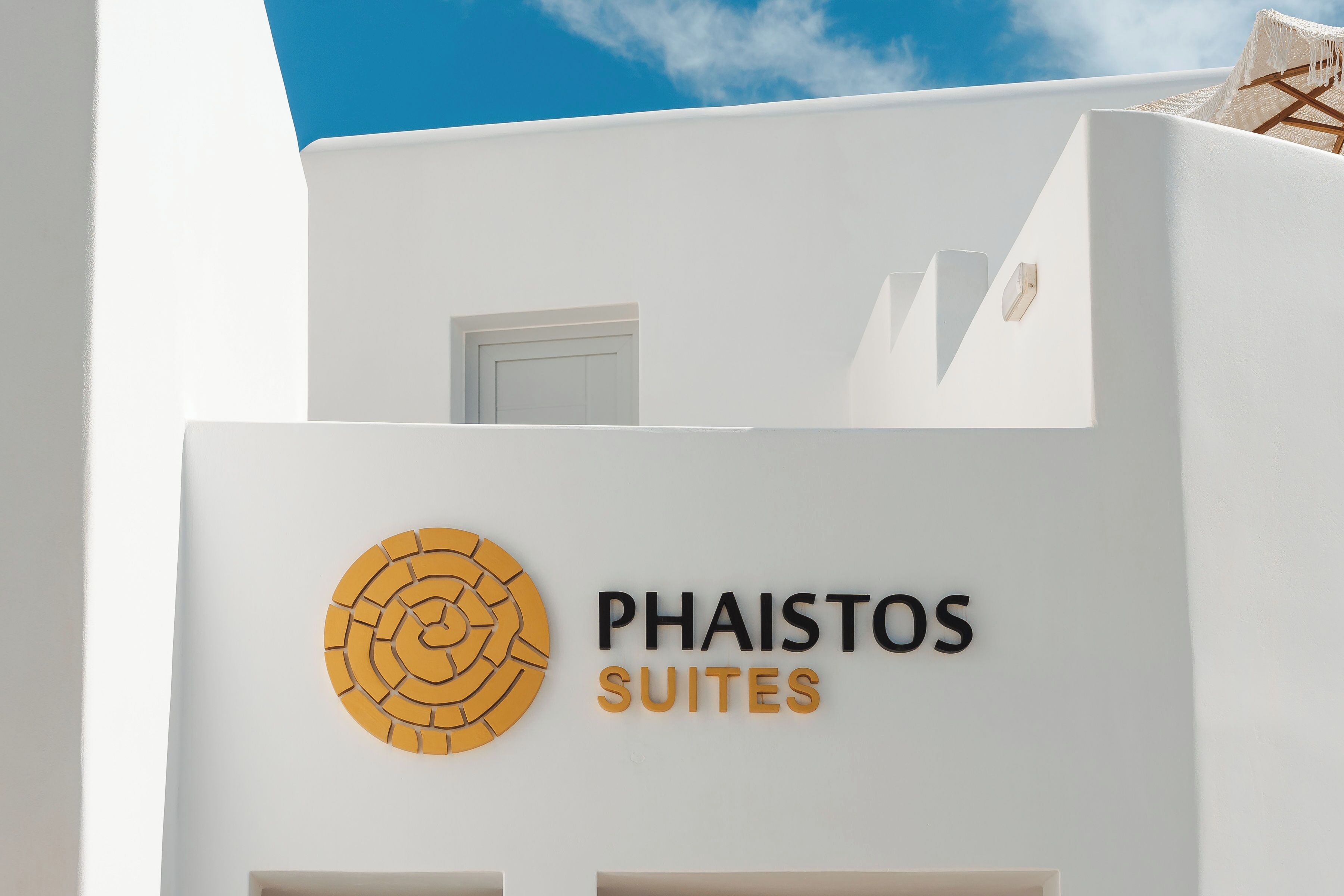 Ein Gebäude mit einem Schild, das „Phaistos Suites“ zeigt, und einem runden Logo.