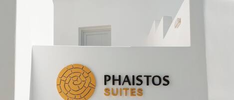 Ein Gebäude mit einem Schild, das „Phaistos Suites“ zeigt, und einem runden Logo.