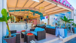Een terras met rieten meubilair, een bar en potplanten.