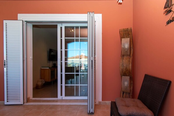 A room with a sliding glass door leading to a balcony, a chair, and a wall-mounted decorative panel.