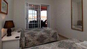 Un dormitorio con cama, una mesita de noche con lámpara, un espejo y vistas al exterior.