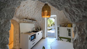Une cuisine chaleureuse avec des meubles blancs, un four encastré et un luminaire suspendu.