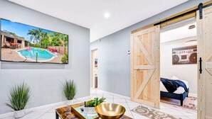 Un moderno salón con vista a la piscina, un cuadro grande y una puerta corrediza tipo granero.