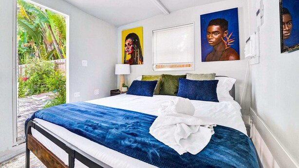 Un dormitorio con cama, ventana y puerta que da a un balcón.