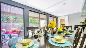 Comedor con una mesa larga dispuesta para cuatro, ventanas grandes y vista a un patio exterior.