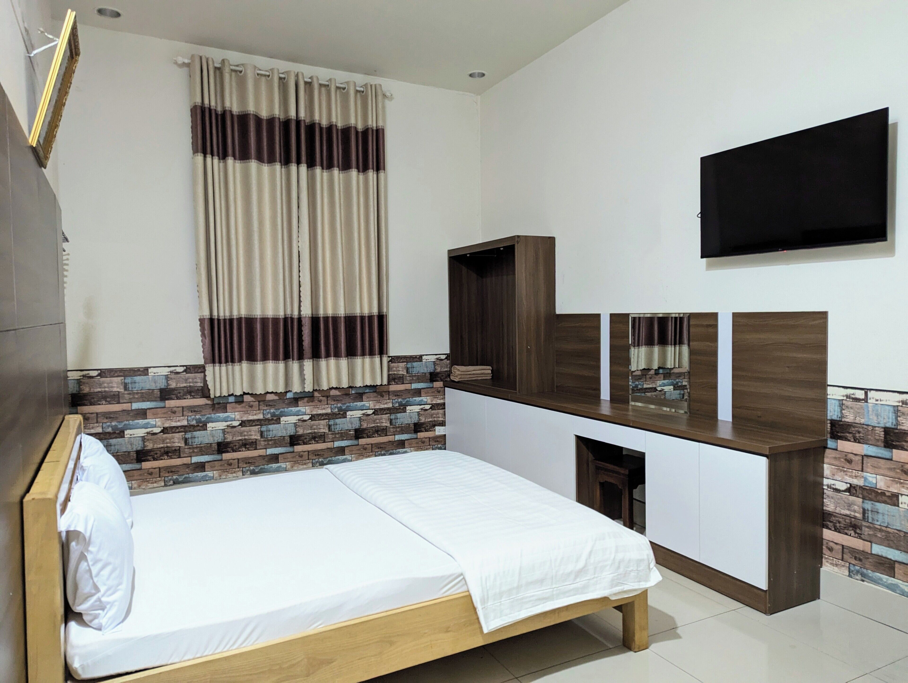 Un dormitorio moderno con una cama de madera, un televisor integrado y una pared con estampado de piedra.