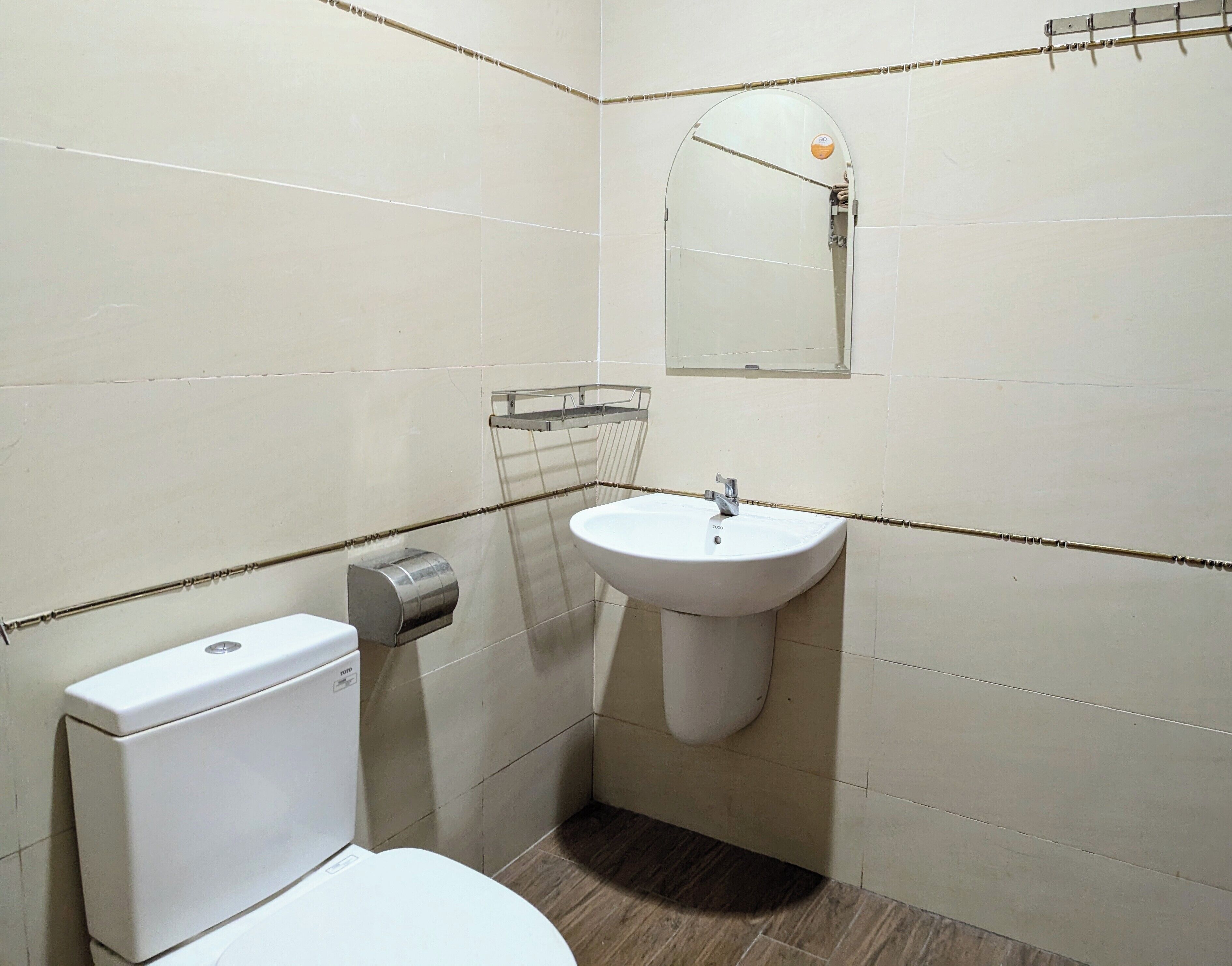 A small bathroom with a toilet, a sink, and a mirror.