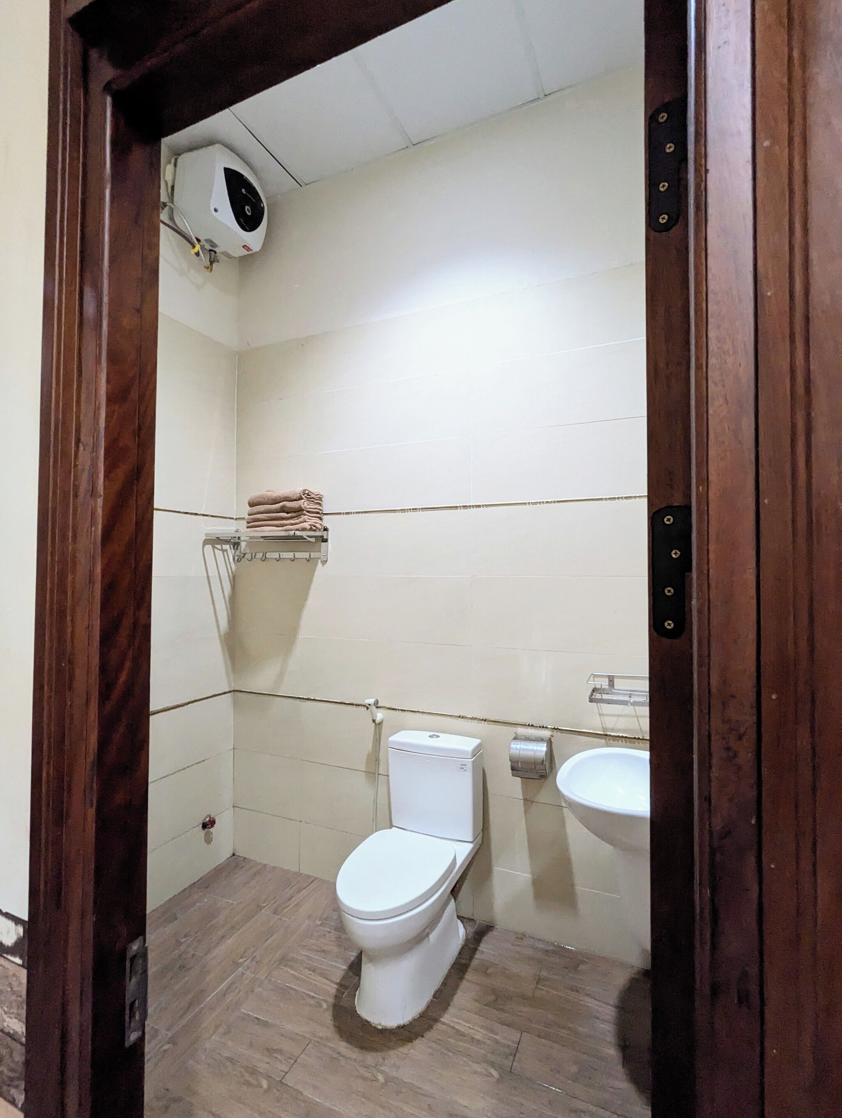 Et lille, enkelt badeværelse med toilet, håndvask og håndklædetørre.