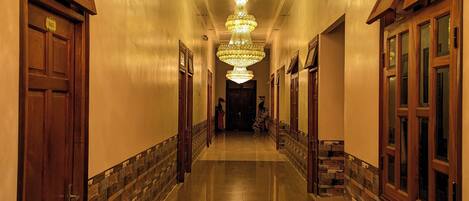 A long, polished hallway with a large, ornate chandelier hanging from the ceiling.