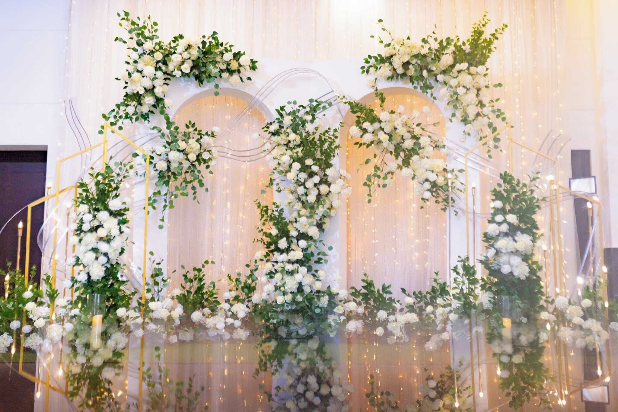 Un escenario decorado con arreglos florales e iluminación.