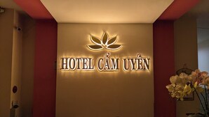 Vastaanottotiski, jossa on kyltti, jossa lukee ”HOTEL CAM UYEN”, ja kukkakimppu.