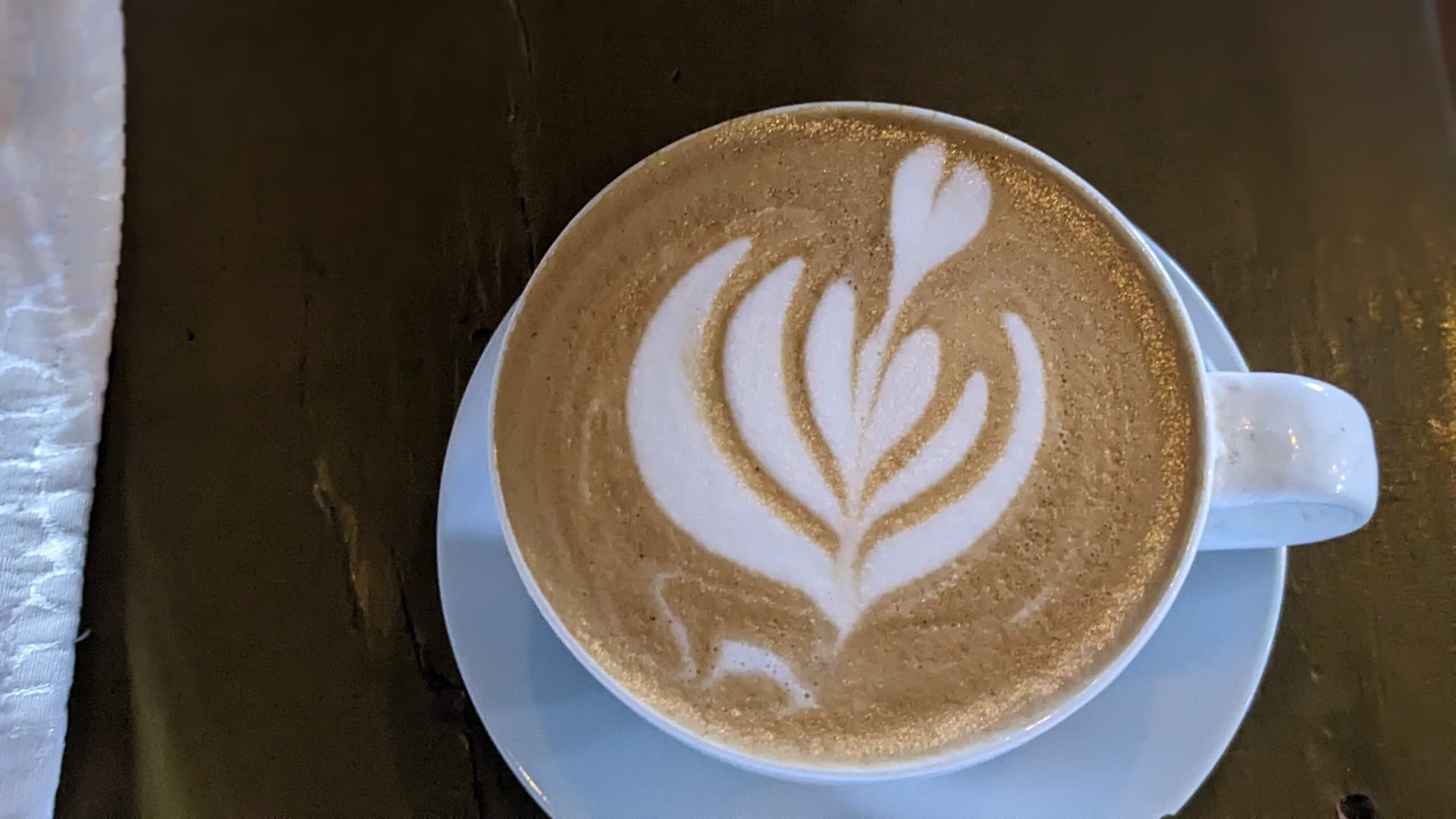 Une tasse de café posée sur une soucoupe ornée d’un motif en forme de feuille.
