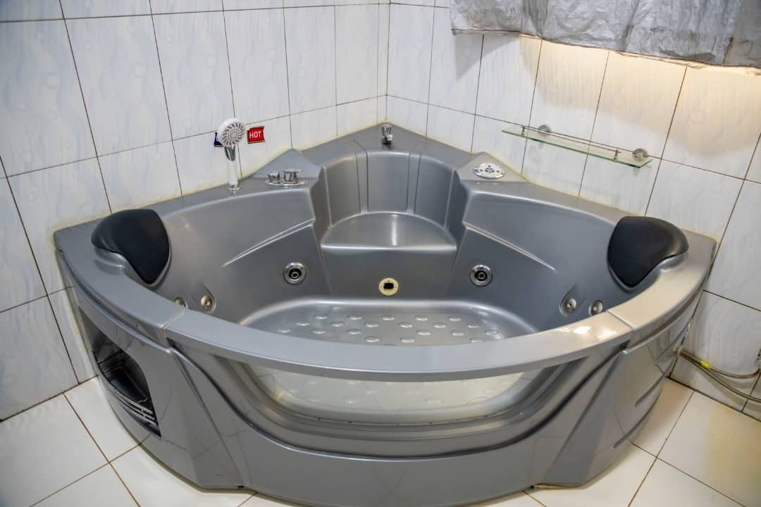 A corner jacuzzi with a glass enclosure, a built-in heater, and a glass shelf above the tub.