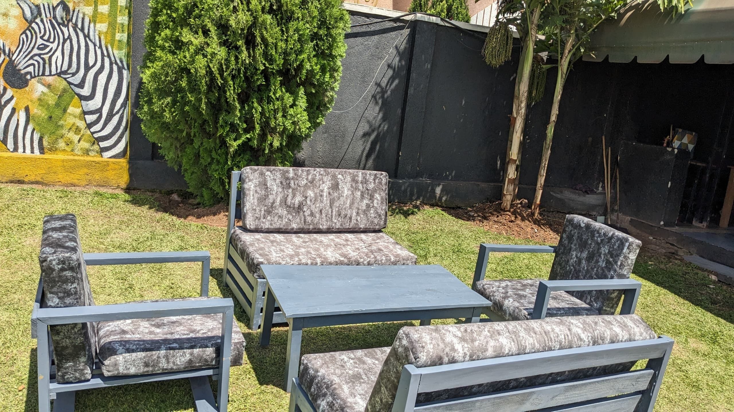 A patio area with a zebra mural, a small tree, and a seating arrangement including a table and chairs.