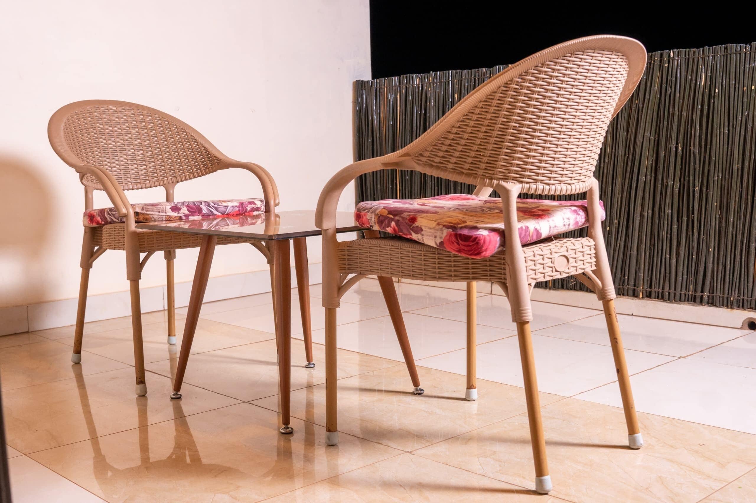 Two wicker chairs with floral cushions and a small table between them.