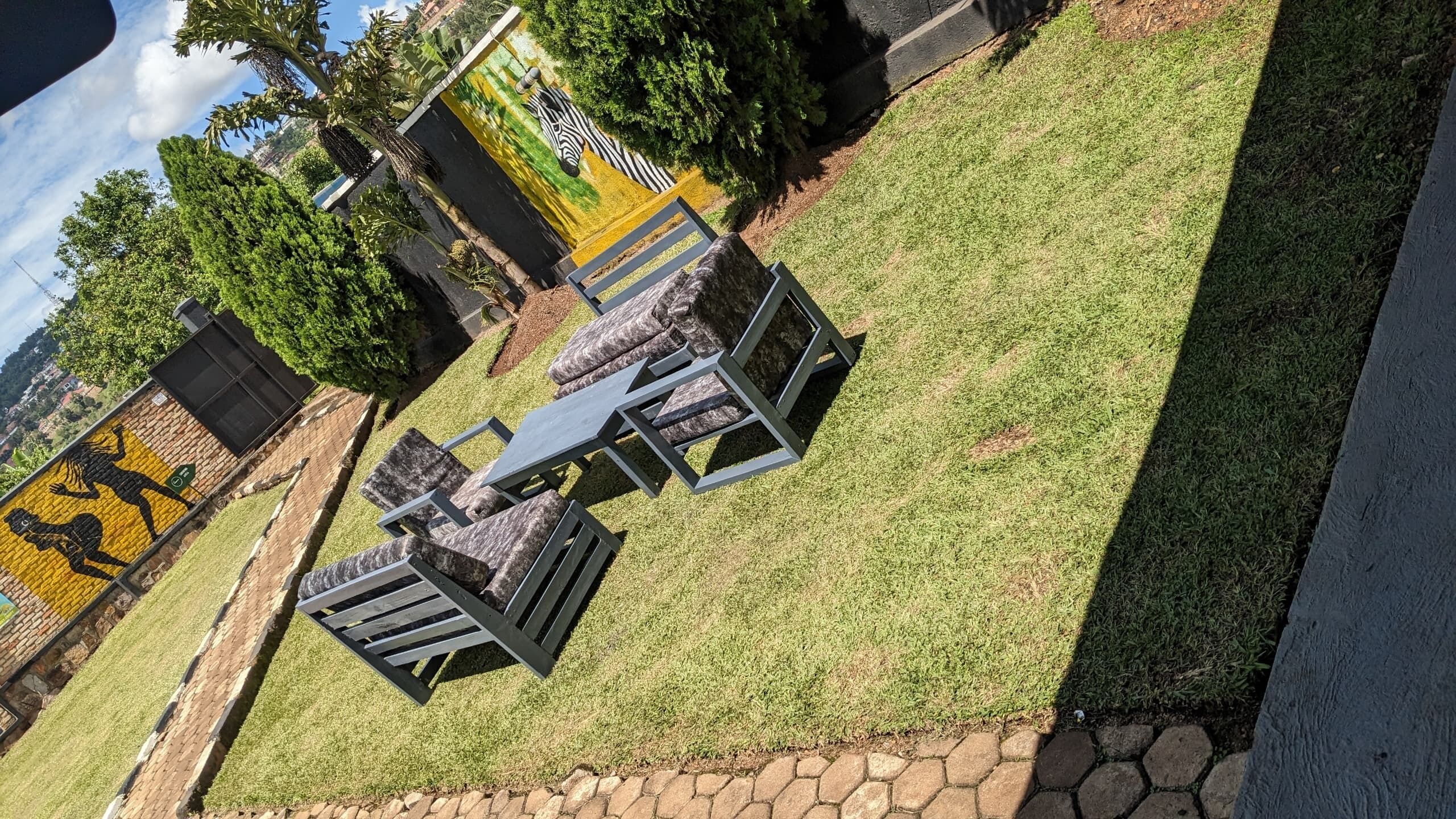 A patio area with a table and chairs, a zebra mural, and a stone wall.