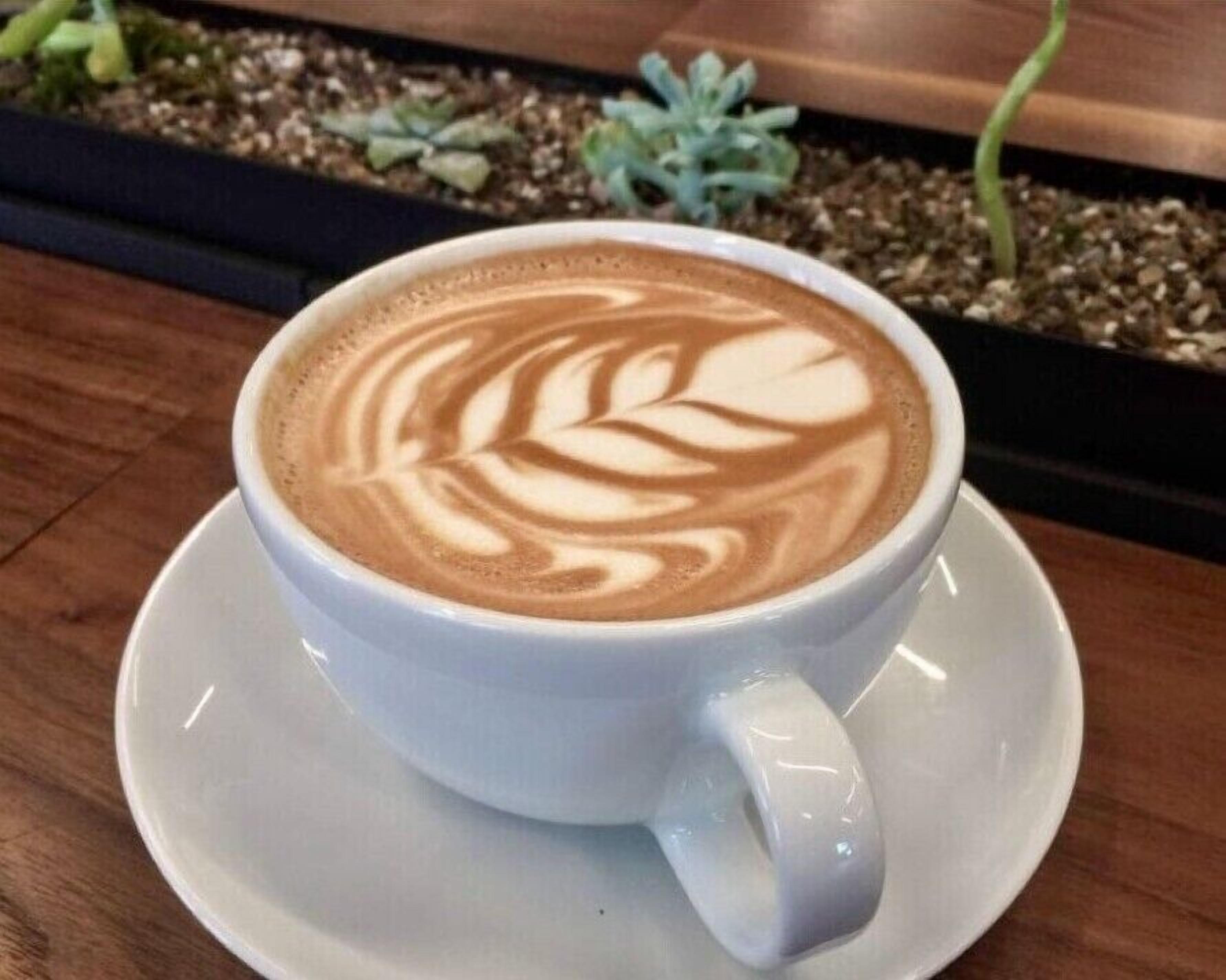 A cup of coffee with latte art on a saucer.
