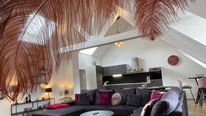 Ein modernes Wohnzimmer mit einem Ecksofa, zwei runden Couchtischen und einem Essbereich mit Tisch und Stühlen.