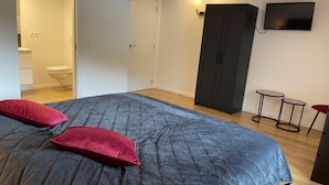Ein Schlafzimmer mit einem großen Bett, einem Kleiderschrank, einem Fernseher und einem kleinen Tisch.