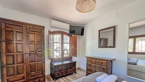 A bedroom with a large bed, wooden wardrobe, a dresser, a television, and a mirror. - Farmhouse in the Picturesque Village of Frigiliana (Frigiliana)
