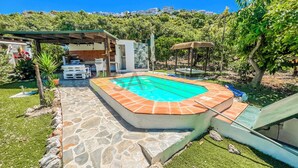 A swimming pool with stone tiles, surrounded by a grassy area and trees. - Farmhouse in the Picturesque Village of Frigiliana (Frigiliana)