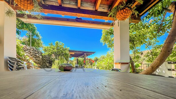 A wooden deck with a stone wall and greenery in the background. - Farmhouse in the Picturesque Village of Frigiliana (Frigiliana)