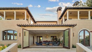 A spacious outdoor patio with a dining area, large windows, and a covered section.