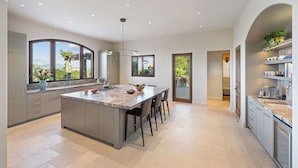 A modern kitchen with a large island, ample natural light, and a view of the outdoors.