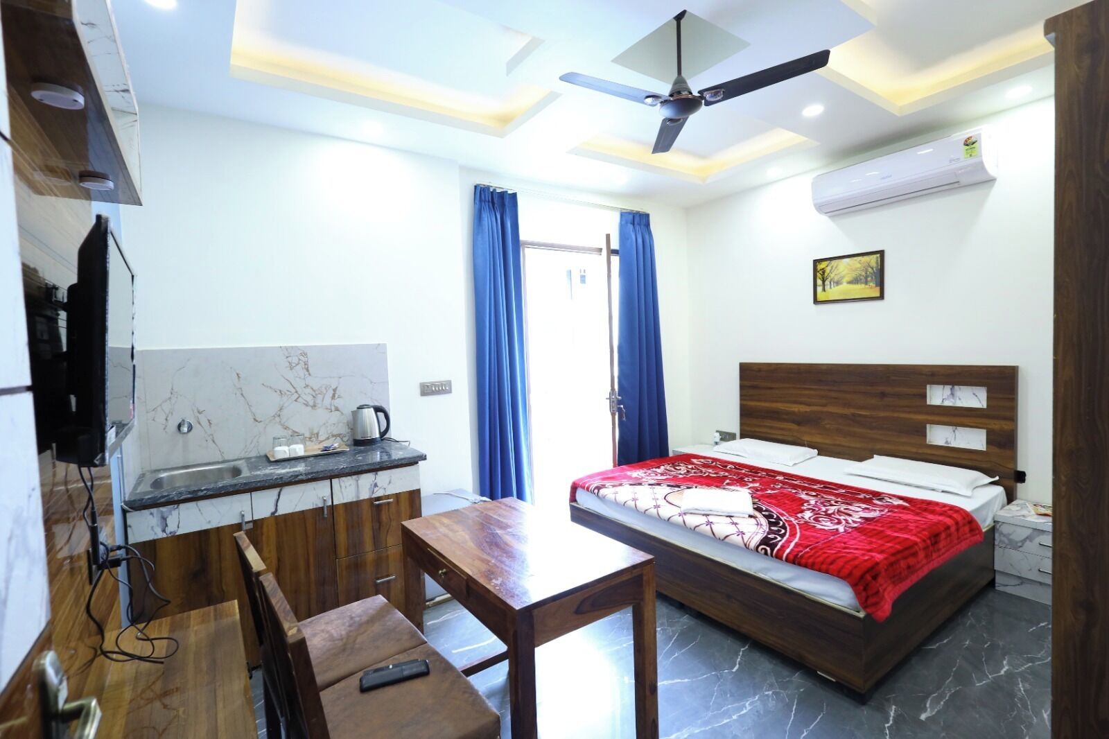 Une chambre d’hôtel équipée d’un lit, d’un bureau, d’une chaise, d’une télévision et d’un ventilateur de plafond.