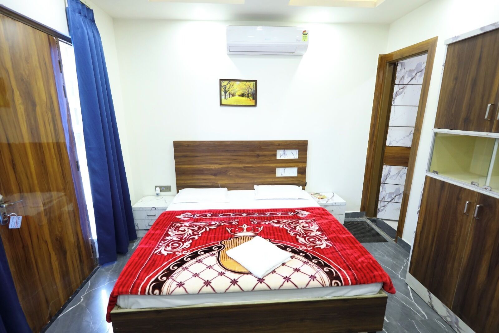 A bedroom with a bed, a nightstand, a wardrobe, and an air conditioning unit.