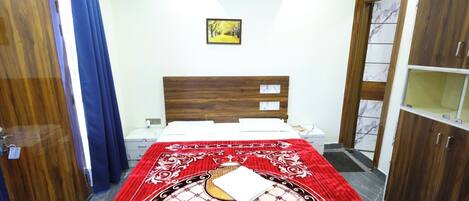 A bedroom with a bed, a nightstand, a wardrobe, and an air conditioning unit.