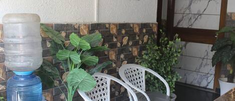 A water dispenser, two wicker chairs, and a tiled wall with a decorative pattern.