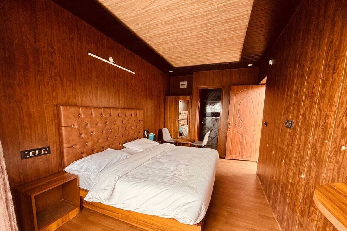 A wooden-finished bedroom with a large bed, bedside tables, and a small seating area.