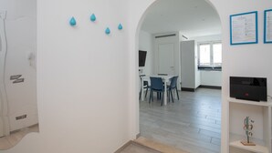 Un interior moderno con comedor, paredes blancas y suelo de madera.
