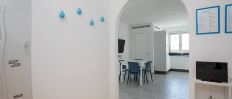 Un interior moderno con comedor, paredes blancas y suelo de madera.