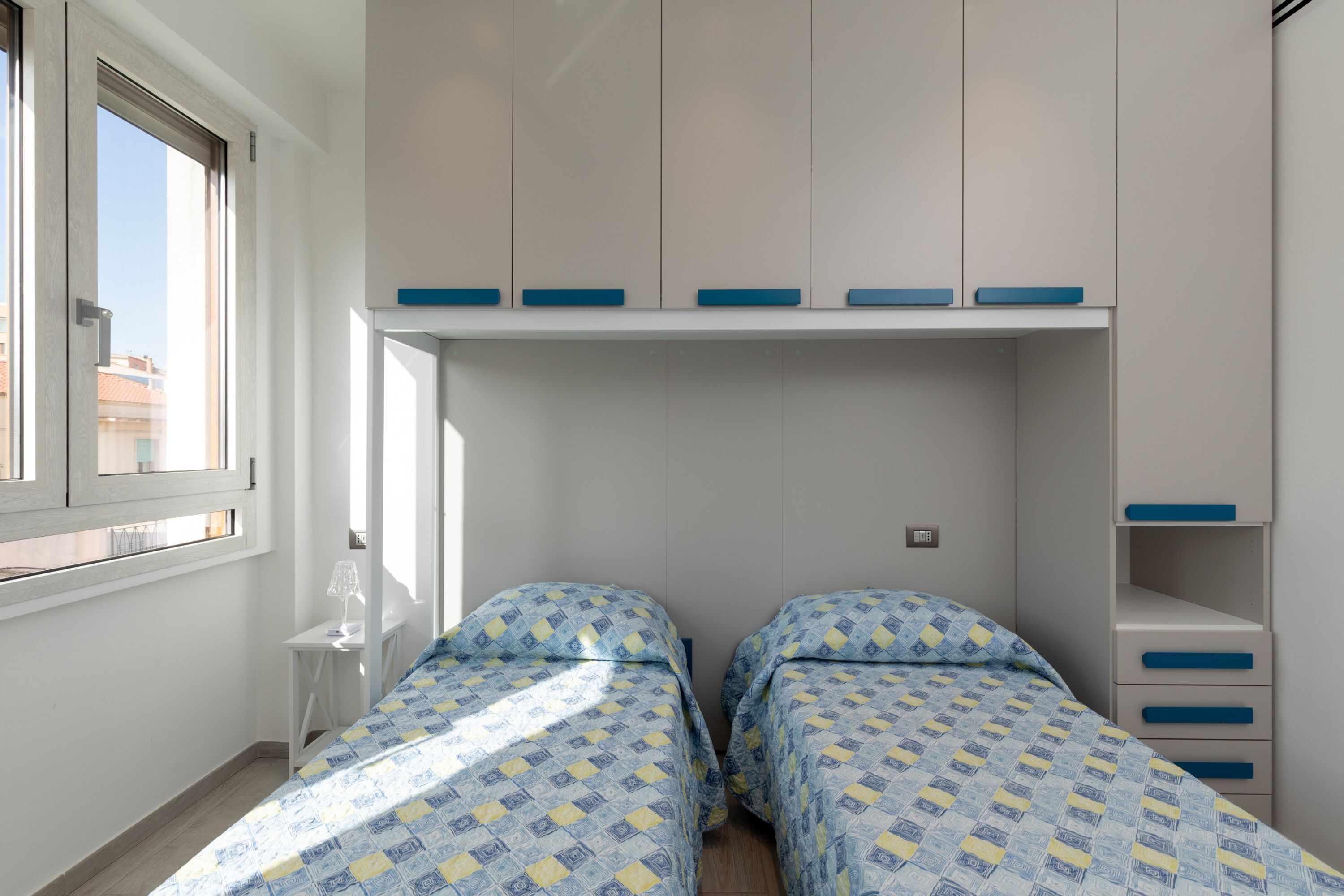 Ein Schlafzimmer mit zwei Betten, einem Fenster und eingebauten Schränken.