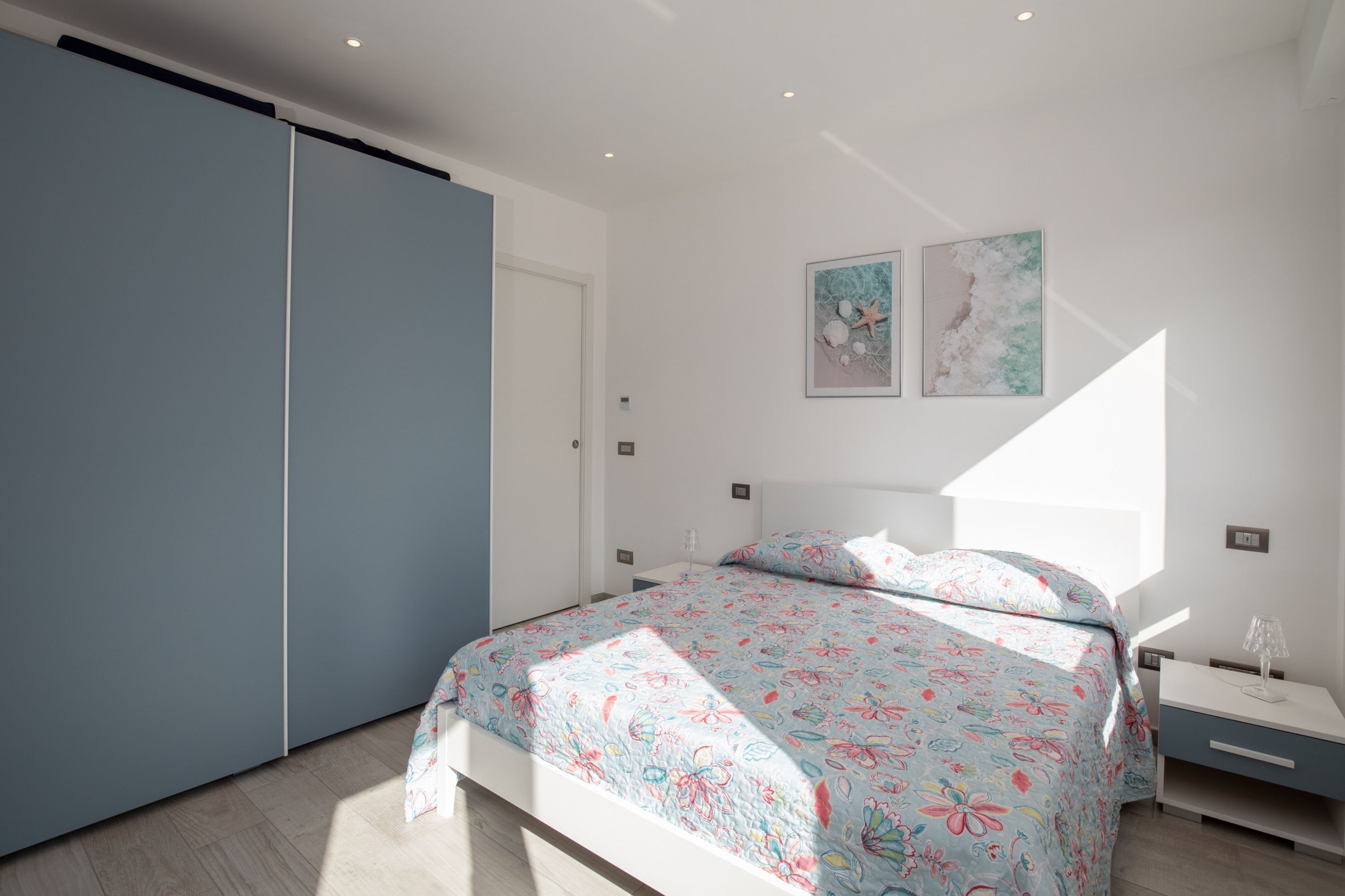 A bedroom with a bed, a nightstand, a lamp, and two wall art pieces.