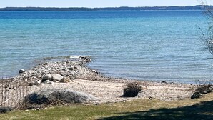 A rocky shoreline with calm water and a clear sky.