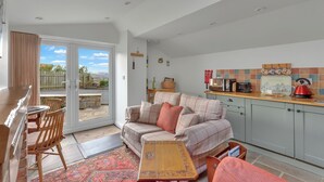 A cozy living room with a sofa, a wooden coffee table, and a dining area with chairs. - The Bothy - North East Escapes (Alnwick)